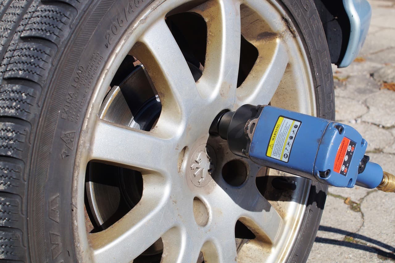 An impact wrench on the wheel nuts of a car