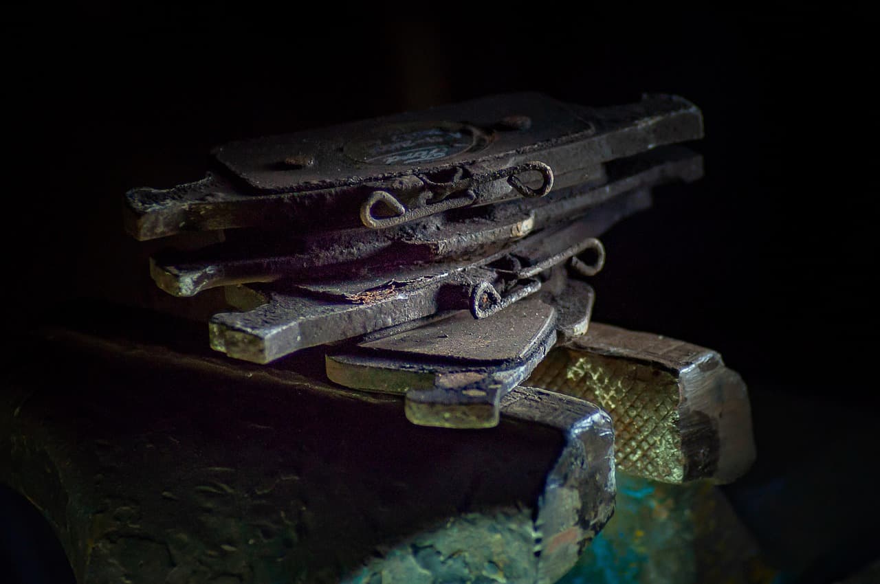 Worn brake pads stacked on a workbench in low light